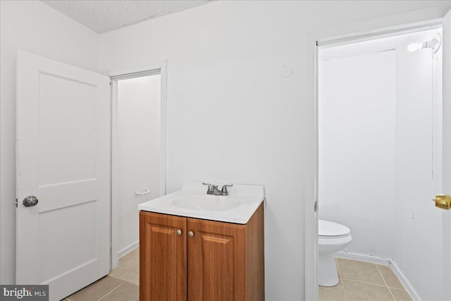 bathroom with tile patterned flooring, a textured ceiling, vanity, and toilet