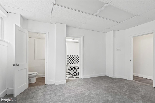 unfurnished bedroom with carpet flooring, a paneled ceiling, ensuite bath, and a closet