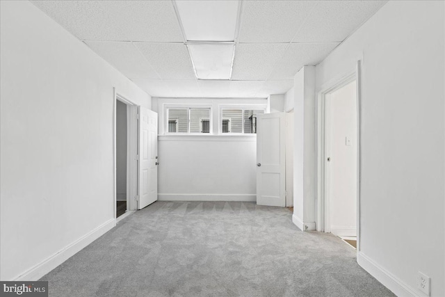 spare room with a paneled ceiling and light colored carpet