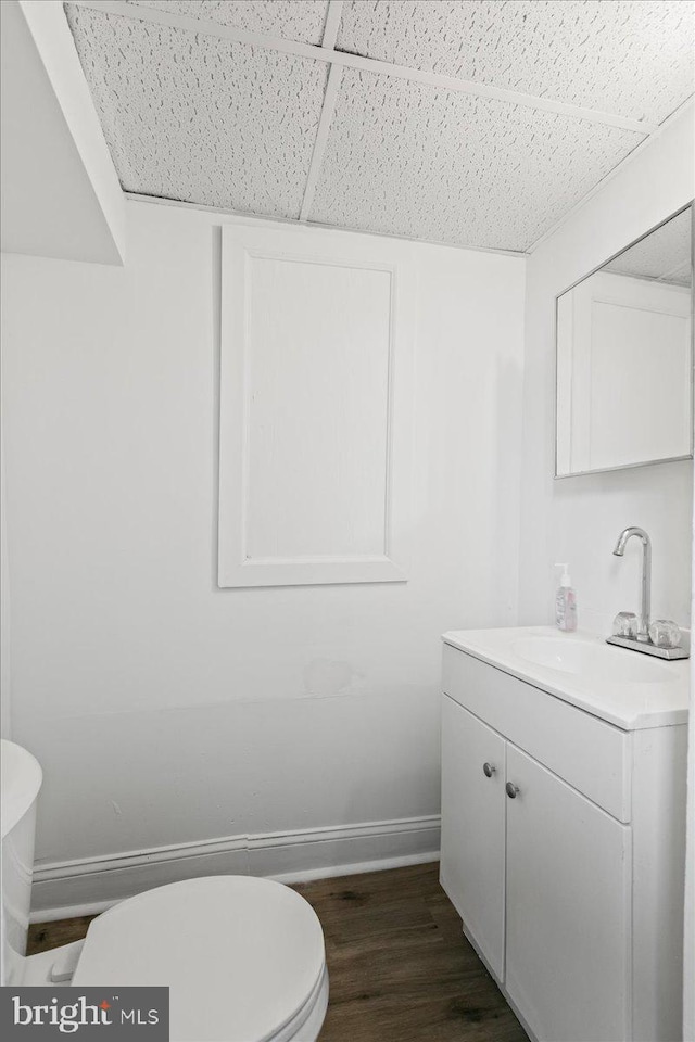 bathroom featuring vanity, hardwood / wood-style floors, a paneled ceiling, and toilet