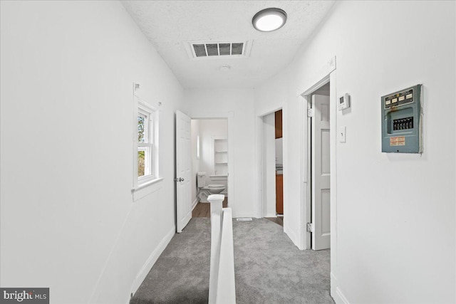 corridor featuring a textured ceiling and light colored carpet