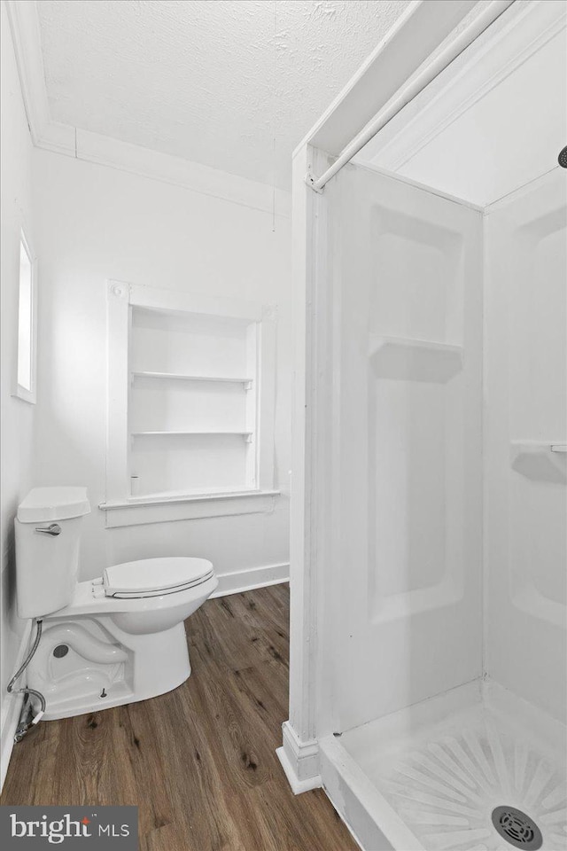 bathroom featuring toilet, wood-type flooring, a textured ceiling, and walk in shower