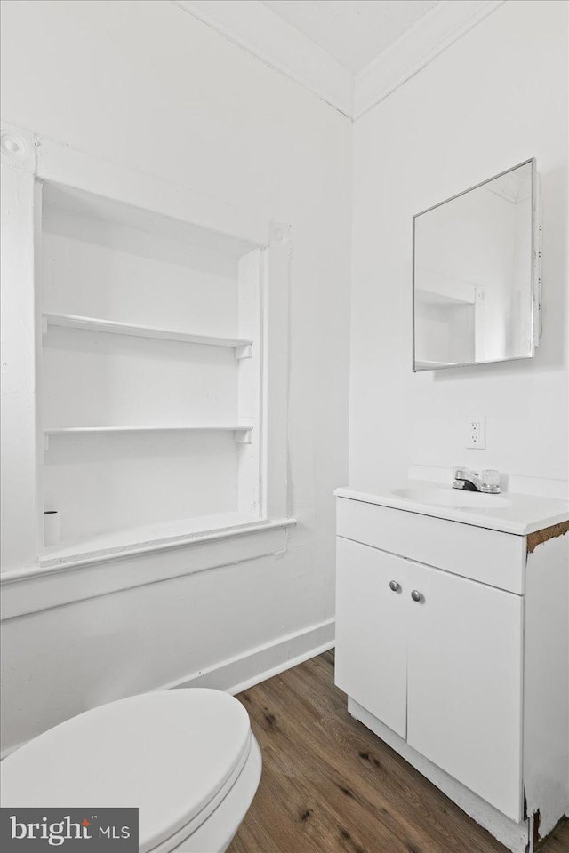 bathroom featuring vanity, hardwood / wood-style flooring, toilet, and ornamental molding