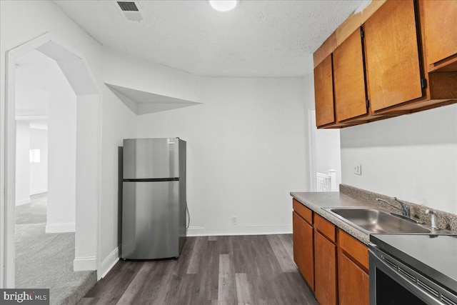 kitchen with dark hardwood / wood-style floors, sink, a textured ceiling, and stainless steel refrigerator