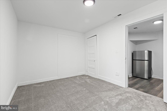 unfurnished bedroom with stainless steel refrigerator, a closet, and dark carpet