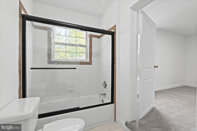 bathroom featuring toilet and bath / shower combo with glass door