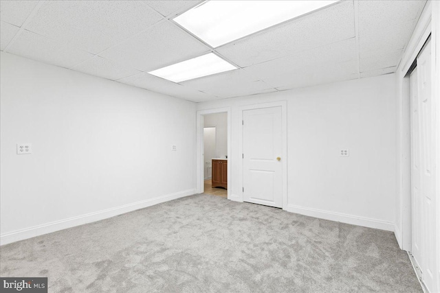 interior space featuring light colored carpet and a drop ceiling