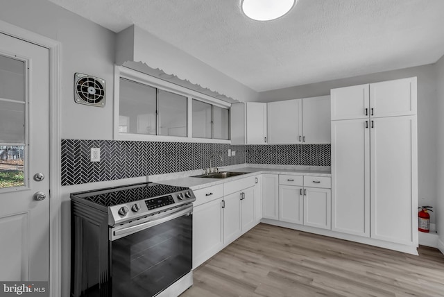 kitchen with white cabinetry, stainless steel range, sink, tasteful backsplash, and light hardwood / wood-style flooring