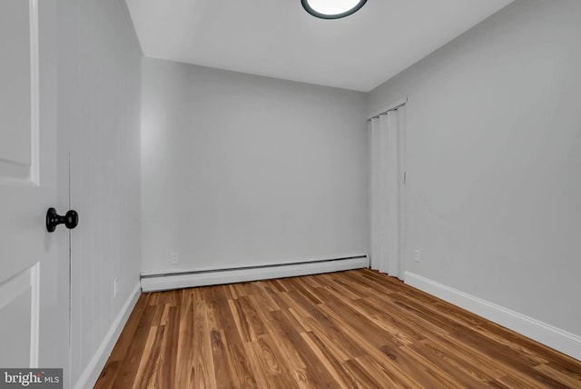 unfurnished room with a baseboard radiator and wood-type flooring