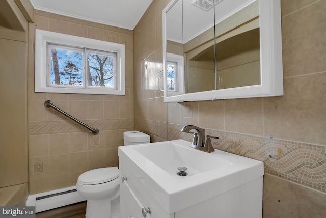 bathroom featuring vanity, crown molding, a baseboard heating unit, tile walls, and toilet