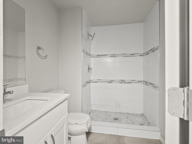 bathroom featuring tiled shower, tile patterned flooring, vanity, and toilet