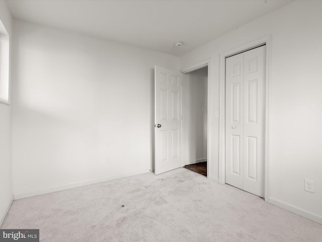 unfurnished bedroom featuring a closet and light colored carpet