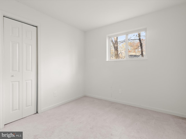 unfurnished bedroom featuring light colored carpet and a closet