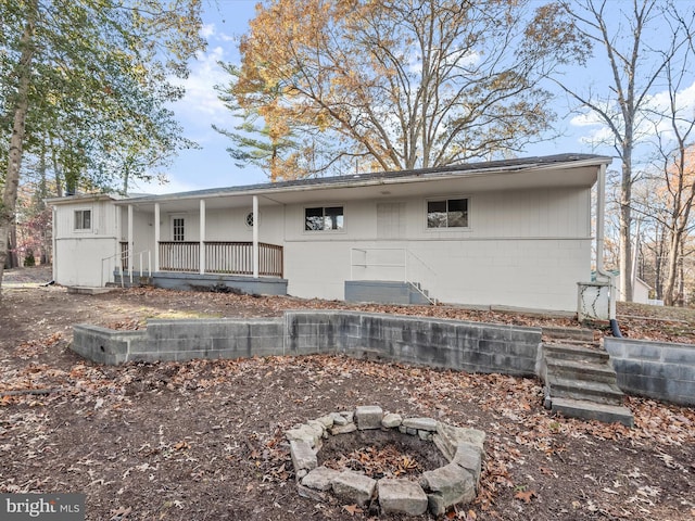 back of property featuring covered porch and an outdoor fire pit