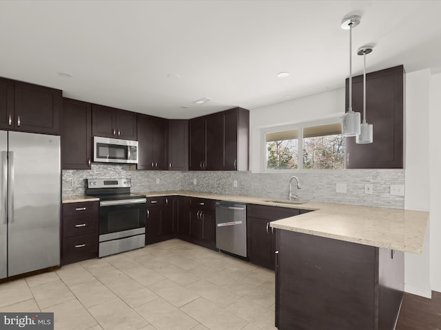 kitchen featuring pendant lighting, sink, decorative backsplash, kitchen peninsula, and stainless steel appliances