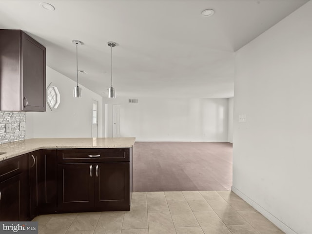 kitchen featuring kitchen peninsula, backsplash, dark brown cabinets, pendant lighting, and light hardwood / wood-style flooring