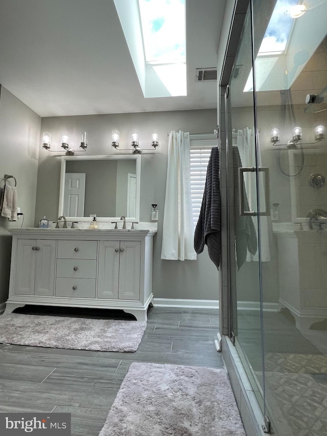 bathroom featuring wood-type flooring, vanity, a skylight, and walk in shower