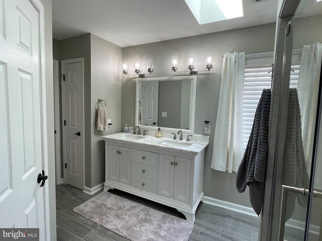 bathroom with vanity, a shower with shower door, wood-type flooring, and a skylight