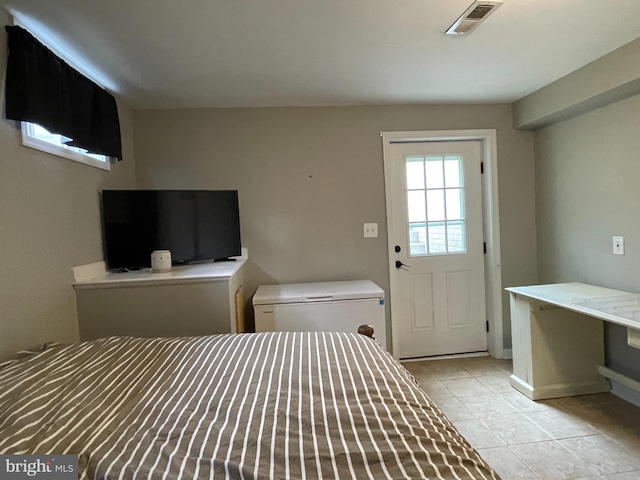 bedroom with light tile patterned floors and fridge