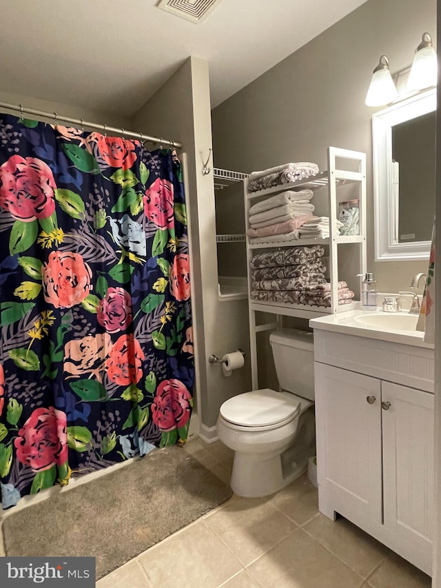 bathroom with tile patterned floors, vanity, toilet, and walk in shower