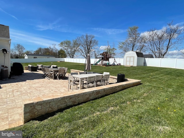 view of yard featuring a storage shed, a playground, and a patio