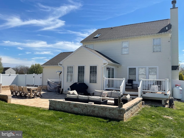 rear view of property featuring outdoor lounge area, a patio, a lawn, and a wooden deck