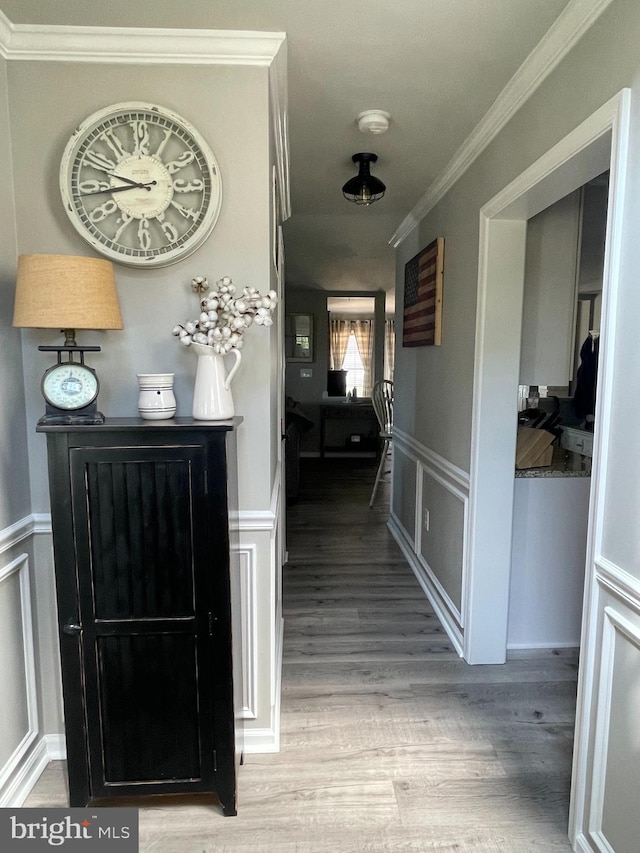 hall with wood-type flooring and ornamental molding