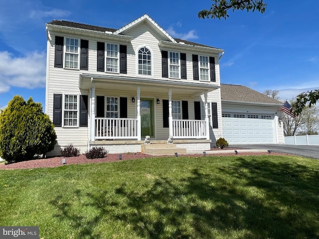 colonial house featuring a porch, a garage, and a front lawn