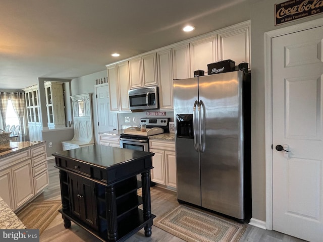 kitchen featuring white cabinetry, light stone counters, light wood-type flooring, and appliances with stainless steel finishes