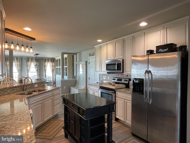 kitchen with pendant lighting, sink, light stone countertops, dark hardwood / wood-style flooring, and stainless steel appliances