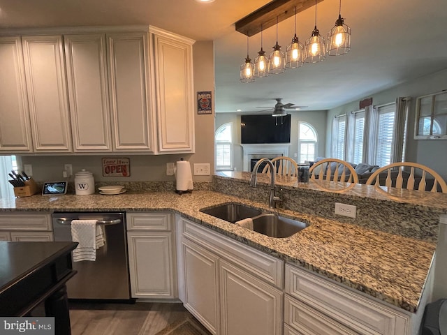 kitchen featuring sink, ceiling fan, decorative light fixtures, light stone counters, and kitchen peninsula