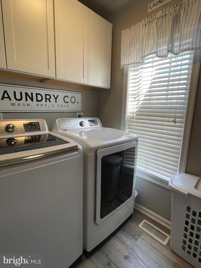 laundry area with washer and dryer, cabinets, and light hardwood / wood-style floors