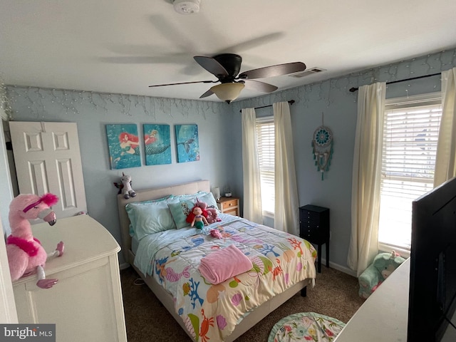 bedroom with dark colored carpet, multiple windows, and ceiling fan