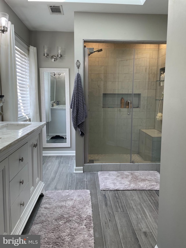 bathroom with hardwood / wood-style floors, vanity, and a shower with shower door