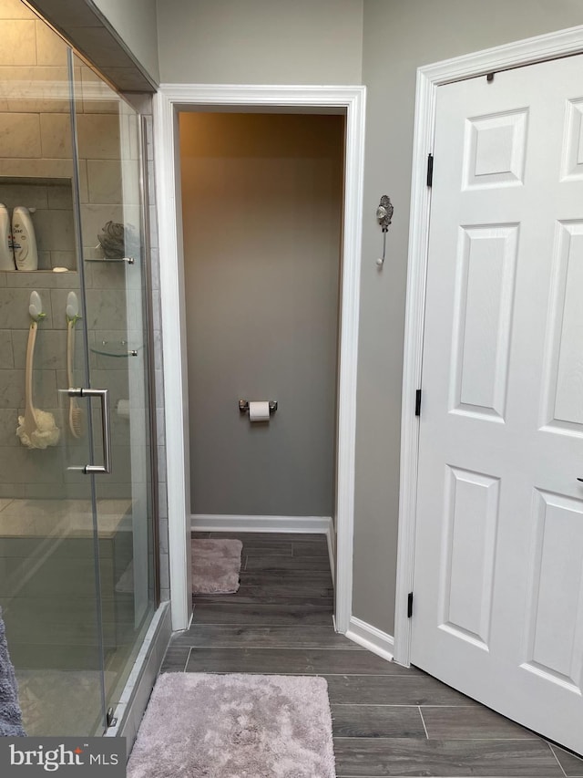 bathroom with an enclosed shower and wood-type flooring