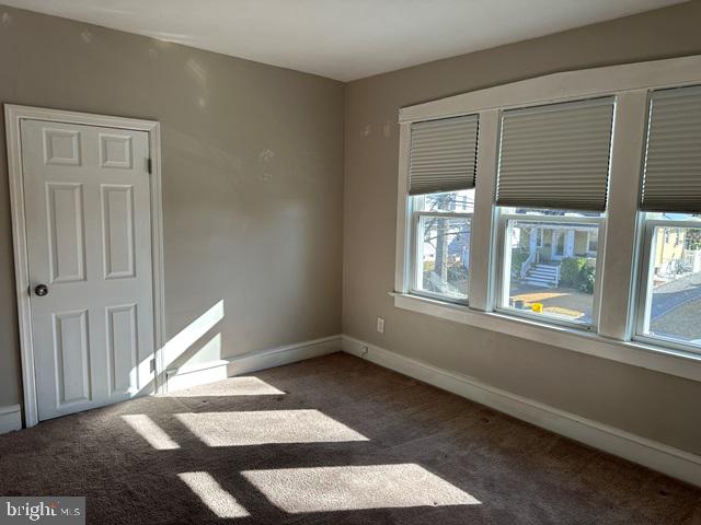 spare room with dark carpet