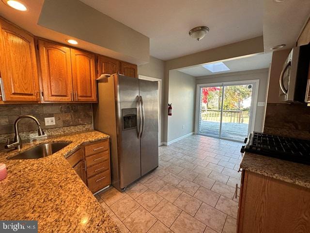 kitchen with appliances with stainless steel finishes, tasteful backsplash, light stone counters, and sink