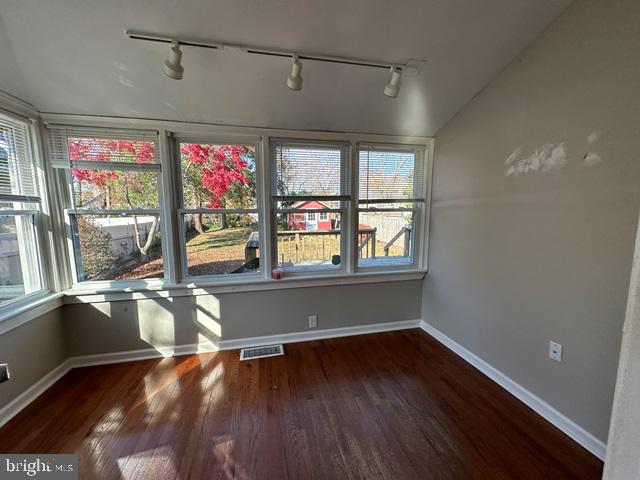 spare room with rail lighting and dark wood-type flooring