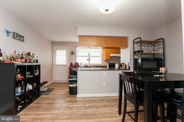 kitchen featuring black appliances, light hardwood / wood-style floors, and kitchen peninsula