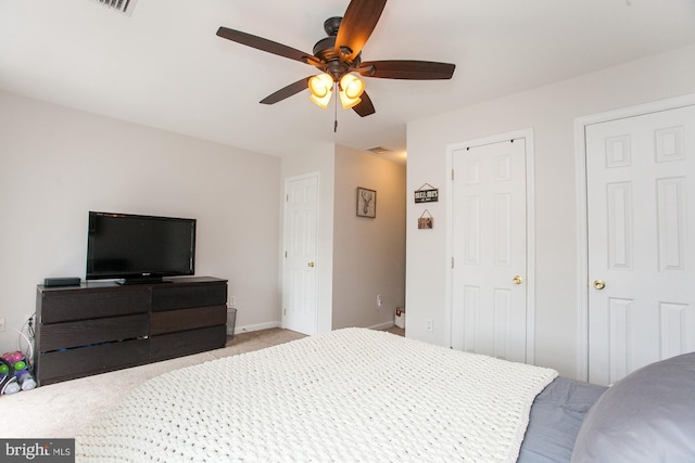 carpeted bedroom with ceiling fan and two closets