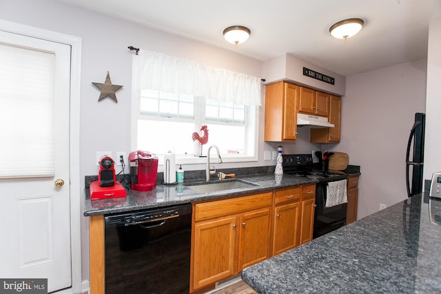 kitchen featuring sink, light hardwood / wood-style floors, dark stone countertops, and black appliances