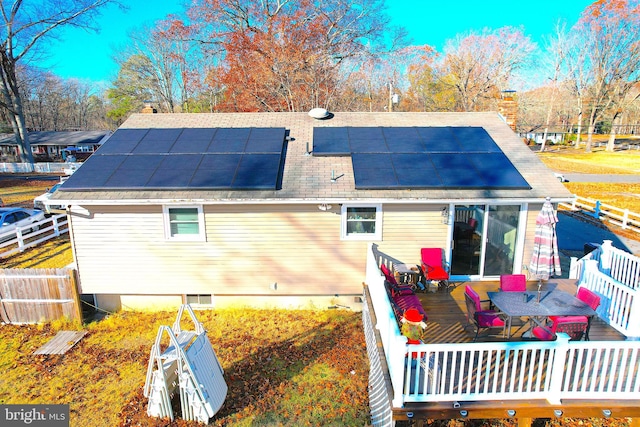 back of house featuring solar panels and a wooden deck