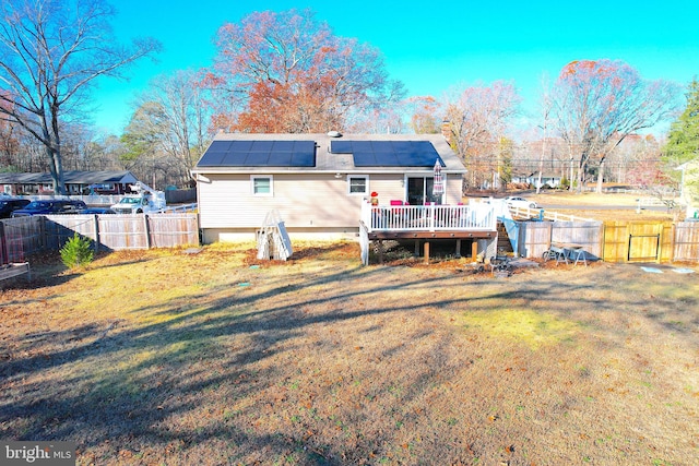 back of property with a lawn, solar panels, and a deck