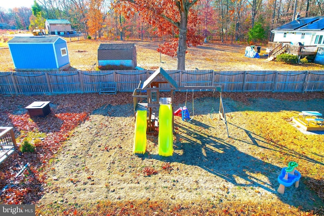 exterior space featuring a trampoline, a playground, and a storage unit