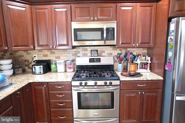 kitchen with light stone countertops, appliances with stainless steel finishes, and tasteful backsplash