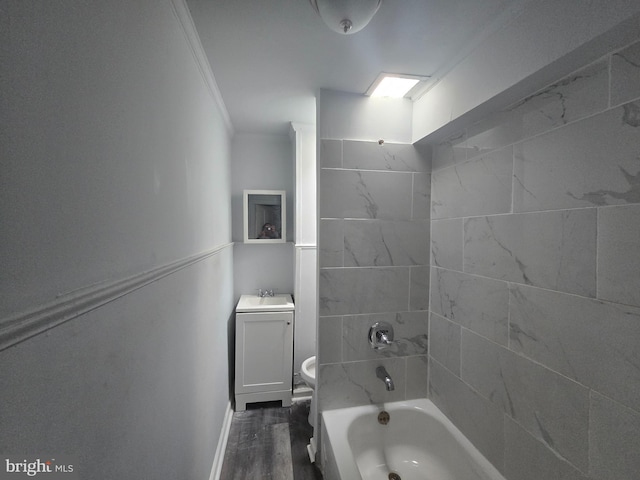 full bathroom featuring hardwood / wood-style floors, vanity, crown molding, tiled shower / bath, and toilet