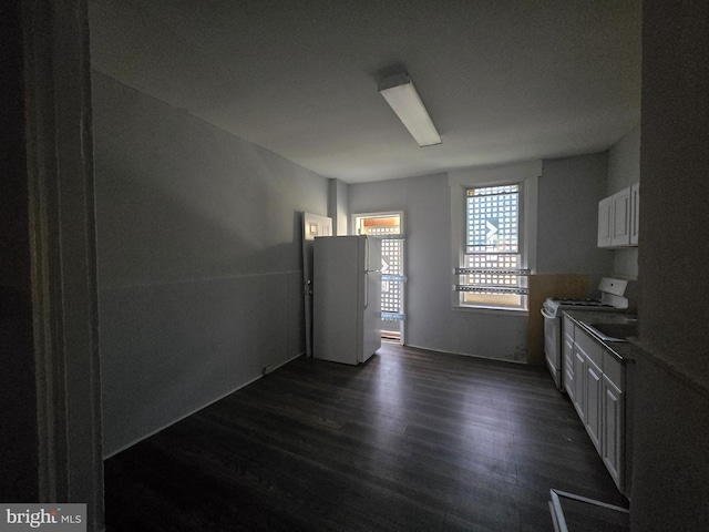 kitchen with white cabinets, dark hardwood / wood-style flooring, and white appliances