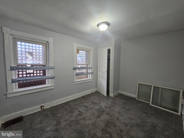 empty room with plenty of natural light and dark carpet