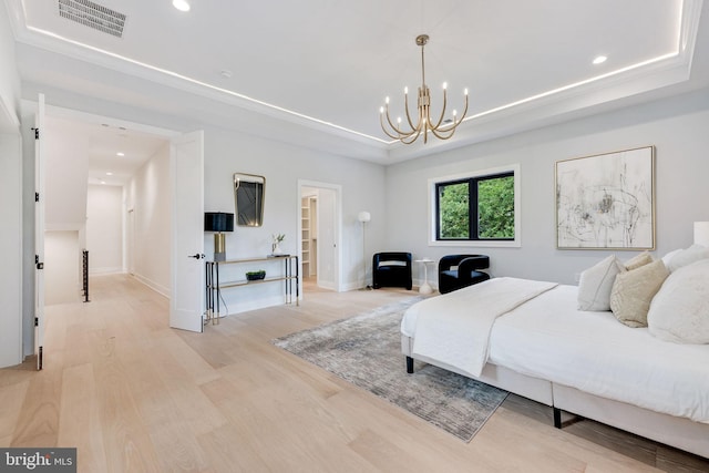 bedroom featuring a notable chandelier, a raised ceiling, and light wood-type flooring