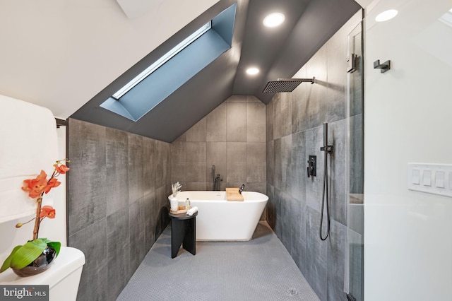 bathroom with tile patterned flooring, shower with separate bathtub, lofted ceiling with skylight, toilet, and tile walls